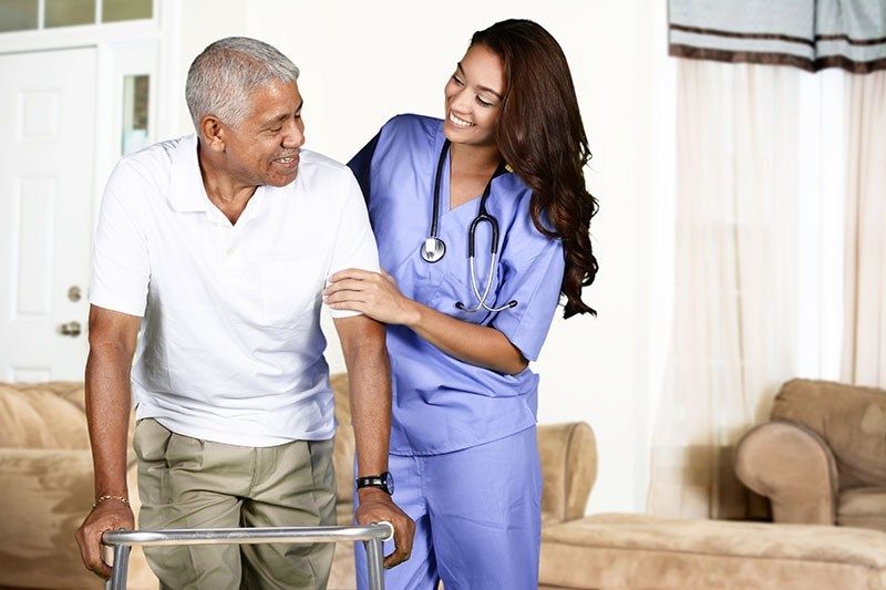 Nurse supporting an older patient using a walking frame